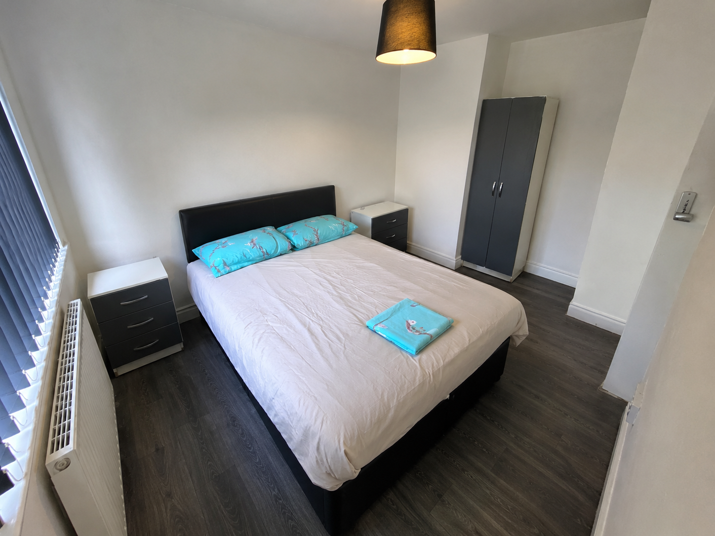 Kings Norton – Room 2: double bed with turquoise pillows, bedside drawers and wardrobe