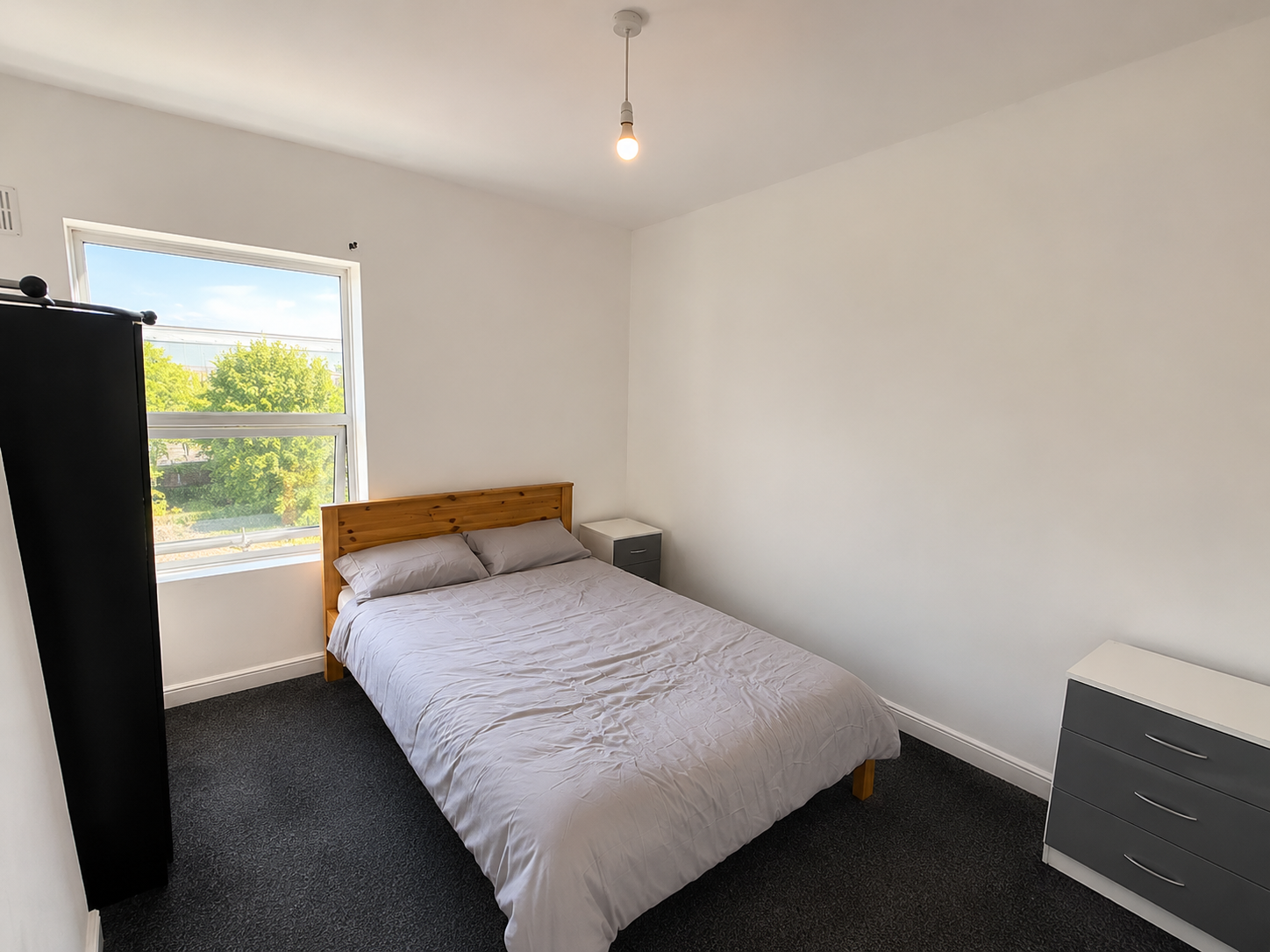 Henswood – Room 2: double bed with wooden headboard beside the window
