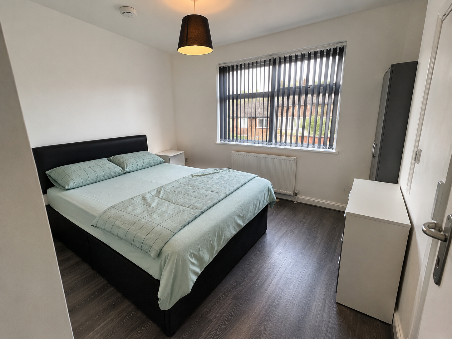 Kings Norton – Room 1: double bed with pale green bedding beside the window and wardrobe
